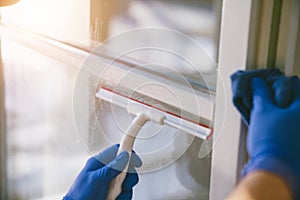 Young man is using a rag and squeegee while cleaning windows.