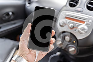 Young man using smart phone mobile phone in car. Close up view. Close up man hand holding charge the battery mobile smart phone in