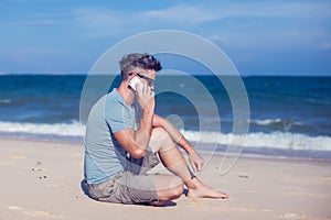 Young man using smartphone on the beach