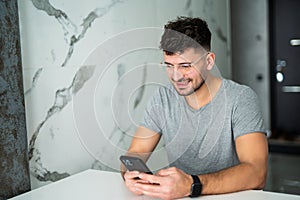 Young man using smartphone, cooking in modern kitchen
