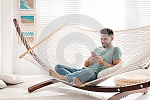 Young man using smartphone in hammock