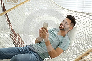 Young man using smartphone in hammock