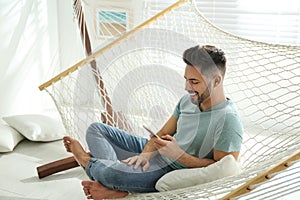 Young man using smartphone in hammock