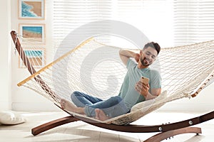 Young man using smartphone in hammock