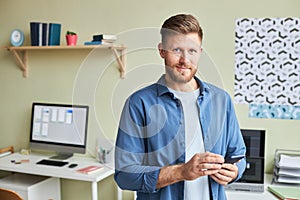 Young man using smartphone and looking at camera office setting