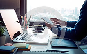 Young man using smartphone with modern work table and computer laptop and cityscapes view from window.Business concepts ideas.