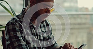 Young man using smartphone sitting in cafe surfing internet