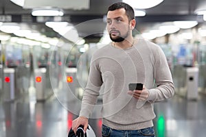 Young man using smartphone to check schedule on subway station
