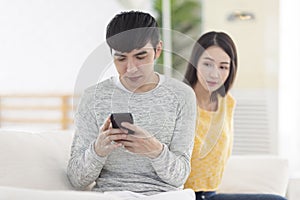 Young man using smartphone.Young woman peeks at man`s smartphone screen