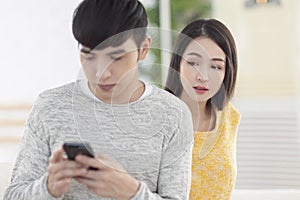 Young man using smartphone.Young woman peeks at man`s smartphone screen