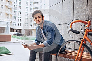 Young man using the tablet sitting on the bench