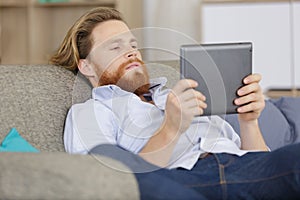 young man using tablet on sofa at home
