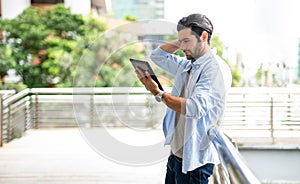 The young man using a tablet to working at out of office. The man wearing casual cloth and feeling thinking and seriously