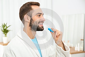 Young man using teeth whitening device