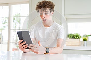 Young man using touchpad tablet scared in shock with a surprise face, afraid and excited with fear expression