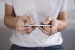 Young man using touchscreen smartphone horizontally. Concept for using technology, shopping online, using mobile apps, texting