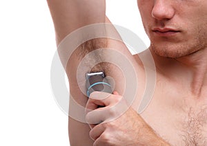 A young man using a trimmer removes hair from underarms. Isolated on white background