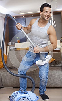 Young man using vacuum cleaner as guitar