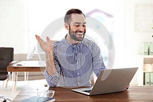 Young man using video chat on laptop in office