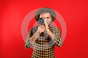 Young man using vintage video camera on red