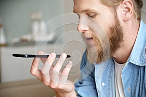 Young man using virtual digital voice assistant on mobile phone, closeup.