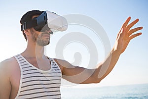 Young man using virtual reality glasses at beach