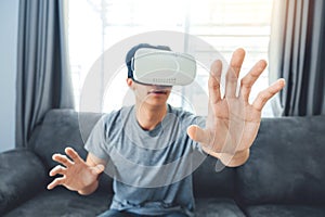 Young man using Virtual Reality Glasses having fun with VR simulator at Home