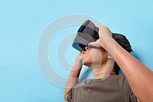 Young man using virtual reality headset on blue background