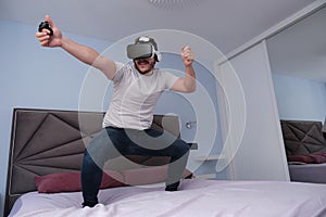 Young man using virtual reality headset standing on bed