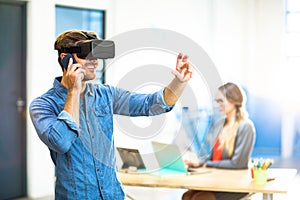 Young man using the virtual reality headset while talking on phone