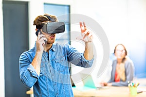 Young man using the virtual reality headset while talking on phone