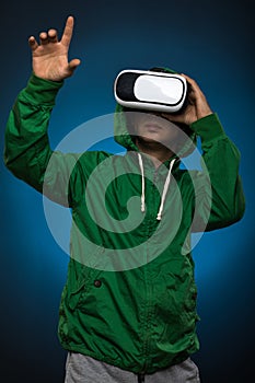 Young man using a VR headset glasses. Man with virtual reality glasses showing gesture. Studio shot