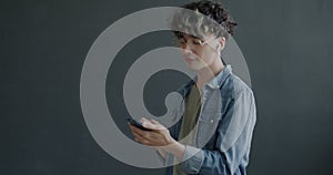 Young man using wireless earphones listening to music dancing having fun on grey color background