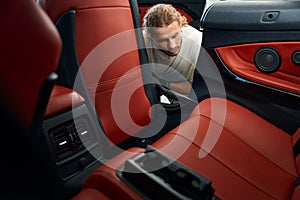 Young man vacuums the interior of a car