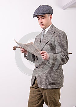 Young man in vintage clothes with hat, reading newspaper, 1940 s