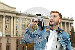 Young man with vintage video camera on street