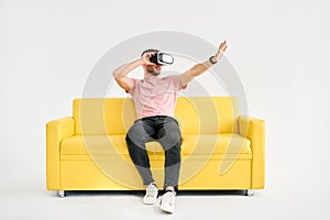 Young man in virtual reality headset playing video games and trying to touch something with hands