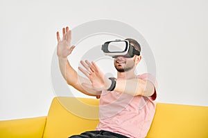 Young man in virtual reality headset playing video games and trying to touch something with hands