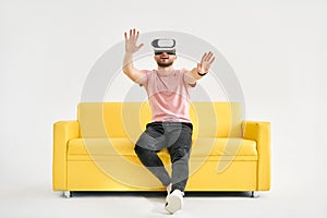 Young man in virtual reality headset playing video games and trying to touch something with hands