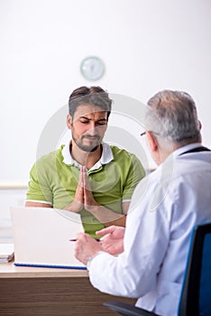 Young man visiting old male doctor