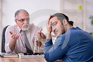 Young man visiting old male jeweler