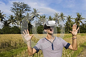 Young man with VR glasses in the tropical rice field