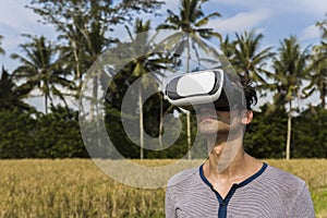 Young man with VR glasses in the tropical rice field