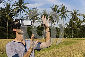 Young man with VR glasses in the tropical rice field