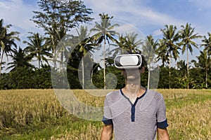 Young man with VR glasses in the tropical rice field