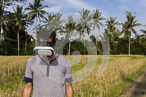 Young man with VR glasses in the tropical rice field