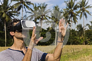 Young man with VR glasses in the tropical rice field