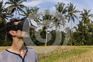 Young man with VR glasses in the tropical rice field