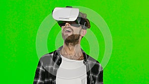 Young man with VR virtual reality headset on his head. Green screen. Close up