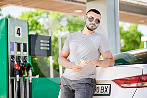 Young man waiting for petrol station operator to pay for fuel.
